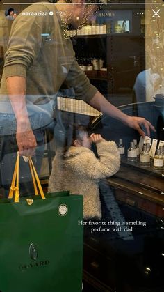 a man holding a child in his arms while looking through a window at the store