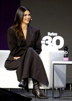 a woman sitting on top of a white couch in front of a tv screen and smiling