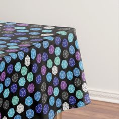 a black table cloth with blue, purple and green dices on it in front of a white wall