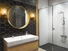 a bathroom with a sink, mirror and shower stall in black and white tile on the wall