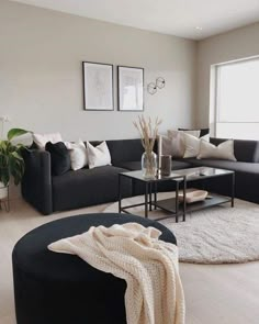 a living room filled with black couches and white rugs on top of a hard wood floor