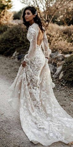 a woman in a wedding dress standing on a dirt road