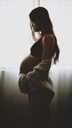 a pregnant woman standing in front of a window