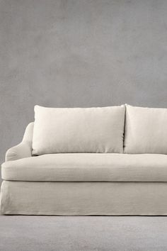 a white couch with two pillows on it's back and the seat upholstered