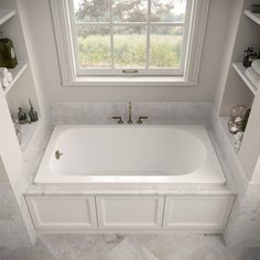 a white bath tub sitting under a window in a bathroom next to two shelves filled with toiletries