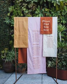 three banners with words on them in front of some plants