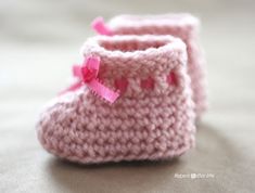 a pair of pink crocheted baby booties sitting on top of a table