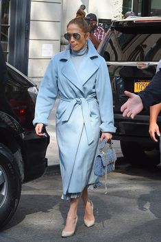 a woman in a blue trench coat is walking