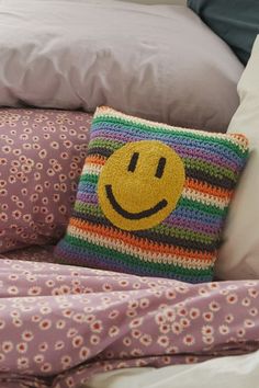 a crocheted smiley face pillow sitting on top of a bed