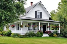 a white house with flowers on the front porch