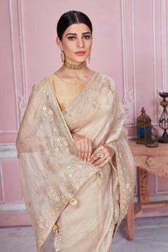 Flaunt your elegant style on festive occasions in this stunning beige embroidered tissue silk saree. It comes with a matching blouse piece. Disclaimer: The shown stitched blouse on the model is for display purpose only. The saree comes with a matching blouse piece and finished with fall and piko. Cream Saree With Intricate Embroidery For Festivals, Cream Tissue Silk Traditional Wear With Sheer Dupatta, Designer Raw Silk Cream Saree, Cream Traditional Wear With Sheer Dupatta In Tissue Silk, Beige Chanderi Embroidered Fabric For Wedding, Beige Art Silk Saree For Wedding, Festive Beige Blouse Piece With Traditional Drape, Festive Beige Tussar Silk Traditional Wear, Festive Cream Raw Silk Saree