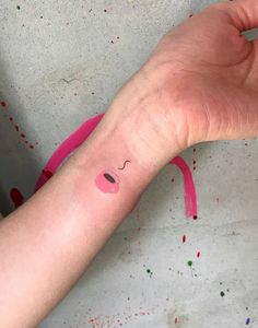 a person's hand with a pink wristband and face painted on the arm