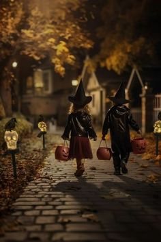 two children dressed up as witches walking down the street with pumpkins in their hands