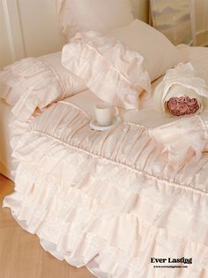 a bed with ruffled sheets and a cup of coffee on the end of it