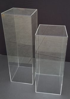 two clear vases sitting side by side on a gray surface, one is empty