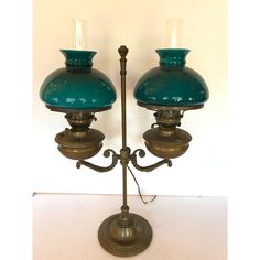 two green glass lamps sitting on top of a metal stand with one light on it's side