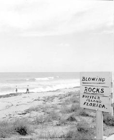 black and white photograph of a sign on the beach that reads blowing rocks outer island florida