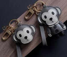 two keychains with monkeys on them sitting on a wooden table next to each other