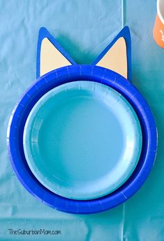 a blue paper plate with a cat face on it next to a cup and napkin