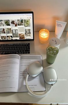 an open book sitting on top of a desk next to a laptop computer and cup