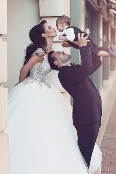 a man and woman kissing while holding a baby