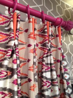 an orange and pink curtain hanging from a rod