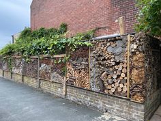 a bunch of wood stacked on top of each other in front of a brick building