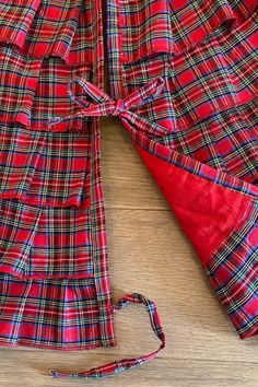 a red and black plaid shirt laying on top of a wooden floor next to a tie