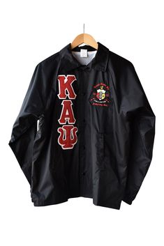 Kappa Alpha Psi Fraternity, Incorporated crossing line jacket with the Greek letters. Kappa Alpha Psi fully embroidered via applique down the right side of the front of the jacket. Embroidered on the upper left chest is the Kappa Alpha Psi Coat of Arms. Our jackets are embroidered compared to others that have heat pressed letters and crests. Our letters and crest will not peel off. (Please note that right pocket may be partially sewn shut due to embroidery of the Greek letters). Black Sporty Outerwear With Embroidered Patch, Black Long Sleeve Outerwear With Embroidered Patch, Black Long Sleeve Outerwear With Embroidered Graphics, Black Outerwear With Embroidered Graphics And Long Sleeves, Collegiate Black Long Sleeve Outerwear, Collegiate Long Sleeve Outerwear With Embroidered Patch, School Spirit Outerwear With Letter Print For Winter, School Spirit Letter Print Winter Outerwear, Winter School Spirit Outerwear With Letter Print