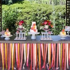 a table topped with lots of cakes and desserts on top of tables covered in ribbons