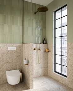 a bathroom with a toilet, shower head and window in the wall next to it