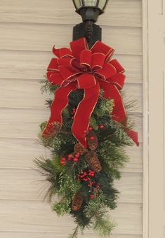 a christmas wreath hanging on the side of a building with a street light attached to it