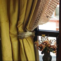 a vase filled with flowers sitting on top of a window sill next to a curtain