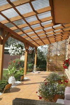 a covered patio with lots of flowers and greenery