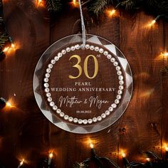 a glass ornament hanging from a christmas tree with lights around it and the number 30 on it