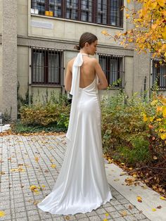 a woman in a white dress is standing on a brick walkway with her back to the camera