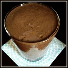 a glass filled with brown liquid sitting on top of a blue and white napkin