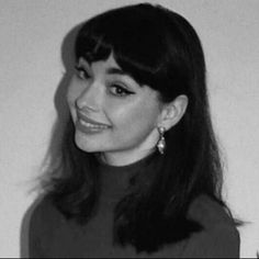 a black and white photo of a woman with long dark hair smiling at the camera