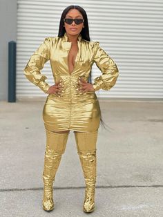 a woman in gold is standing on the street with her hands on her hips and wearing sunglasses