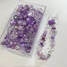 purple beads and bracelets are in a clear box on a white surface with a bead necklace next to it