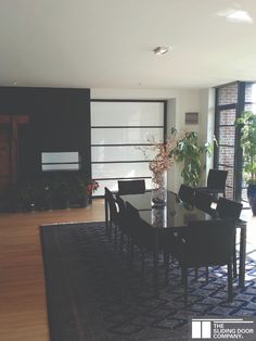 a dining room table and chairs in front of a large window with sliding glass doors