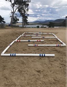 a row of white pipes sitting on top of a sandy beach next to trees and water