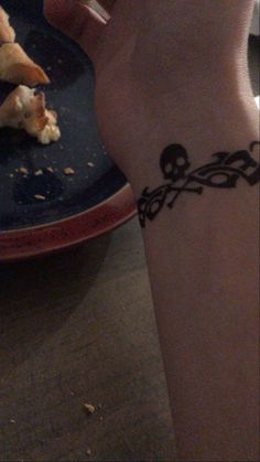 a woman's arm with a tattoo on it and some food in the background