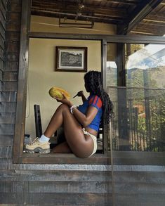 a woman sitting on top of a window sill holding a piece of fruit in her hand