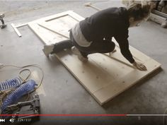 a woman kneeling on top of a piece of plywood in a room filled with tools