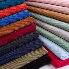 many different colors of sweaters stacked on top of each other, all folded up