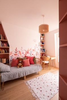 a living room filled with furniture and bookshelves next to a wall covered in pink flowers