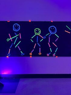 neon stick figures on a black wall in a room with purple lighting and blue walls