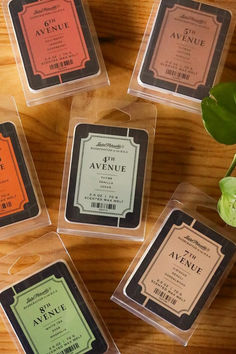 four different types of soaps sitting on top of a wooden table next to a plant