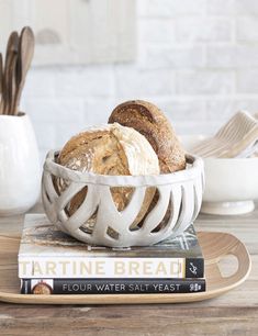 a white bowl filled with bread sitting on top of a wooden table next to a stack of books